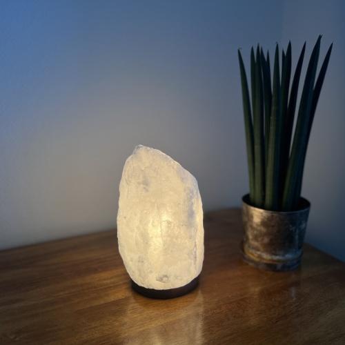 Ljusande saltstenlampa på ett träbord.