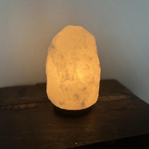 Tänd saltstenlampa på ett mörkt träbord.